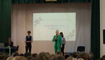 scena w auli, prowadzący, p. pedagog wita zebranych na spotkaniu