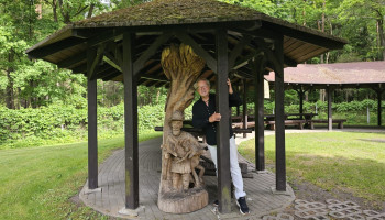 Piotr przy ludowej drewnianej rzeźbie w altance na terenie kwatery myśliwskiej