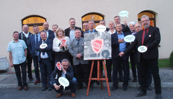 inne pamiątkowe zdjęcie z „plakietkami” i plakatem na sztaludze, przed budynkiem hotelu „Trojak”