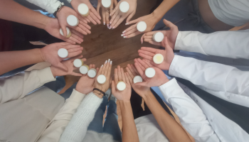 ręce uczestników warsztatów ułożone w krąg z gotowymi próbkami białych kremów