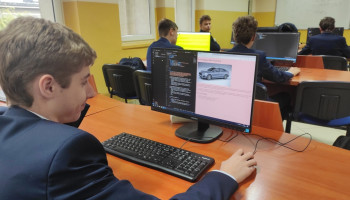 Uczeń przy komputerze, na ekranie strona internetowa z samochodem