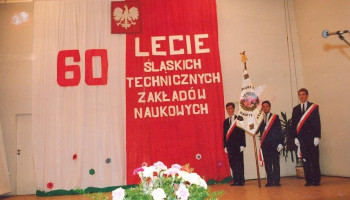 Poczet Sztandarowy Śl.TZN na scenie; na dekoracji godło i napis 60 LECIE ŚLĄSKICH TECHNICZNYCH ZAKŁADÓW NAUKOWYCH (barwy narodowe)