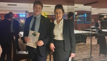 Uczeń prezentujący dyplom w towarzystwie nauczycielki