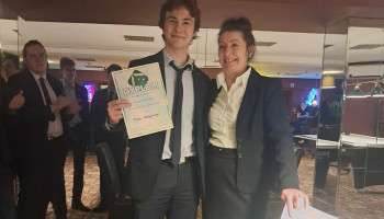 Uczeń prezentujący dyplom w towarzystwie nauczycielki