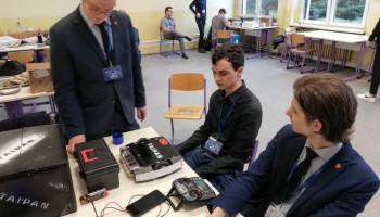 Uczniowie przy stole, na którym leży robot i urządzenie sterujące