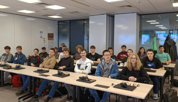 Uczniowie siedzący za stołami w biurze