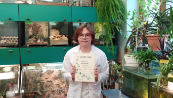 Finalista konkursu z dyplomem, w tle szkolna pracownia ekologiczna