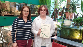 Finalista z dyplomem oraz opiekun, w tle szkolna pracownia ekologiczna