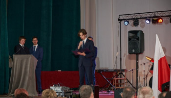 uczeń odczytuje list Prezydenta Miasta Katowice skierowany do absolwentów, z lewej strony prowadzący akademię przy mównicy