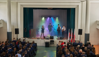 część artystyczna – występ solistki oraz 3 gitarzystów na scenie, po lewej i prawej stronie widoczni uczestniczący w akademii