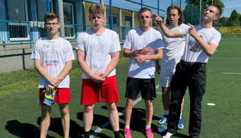 drużyna 4J – 5 zawodników w białych koszulkach sportowych na tle boiska do gry