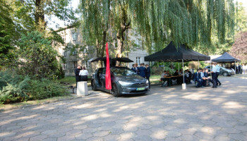 podwórze szkolne – pokaz samochodów Tesla; obok grupy uczniów
