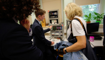 w pracowni mechatroniki na warsztatach szkolnych, uczeń prezentuje osobie zwiedzającej działanie jednego z urządzeń