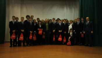 na scenie w auli grupowe pamiątkowe zdjęcie uczniów klasy I, przystępujących do programu, którzy otrzymali prezenty powitalne (w czerwonych workach z napisem Fujitsu)