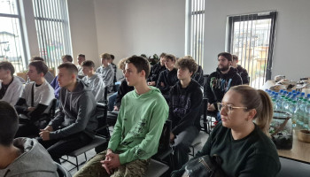 Grupa uczniów i opiekunka podczas wykładu w firmie