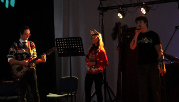 podczas występu: na scenie wokalista z prawej śpiewa, w środku wokalistka, z lewej akompaniuje gitarzysta